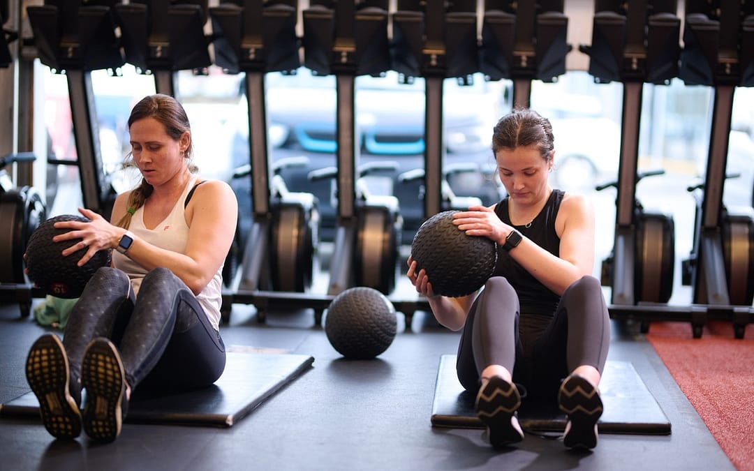 Two women hold weighted slam-balls in a Group Fitness Class.