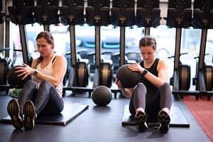 Two women hold weighted slam-balls in a Group Fitness Class.